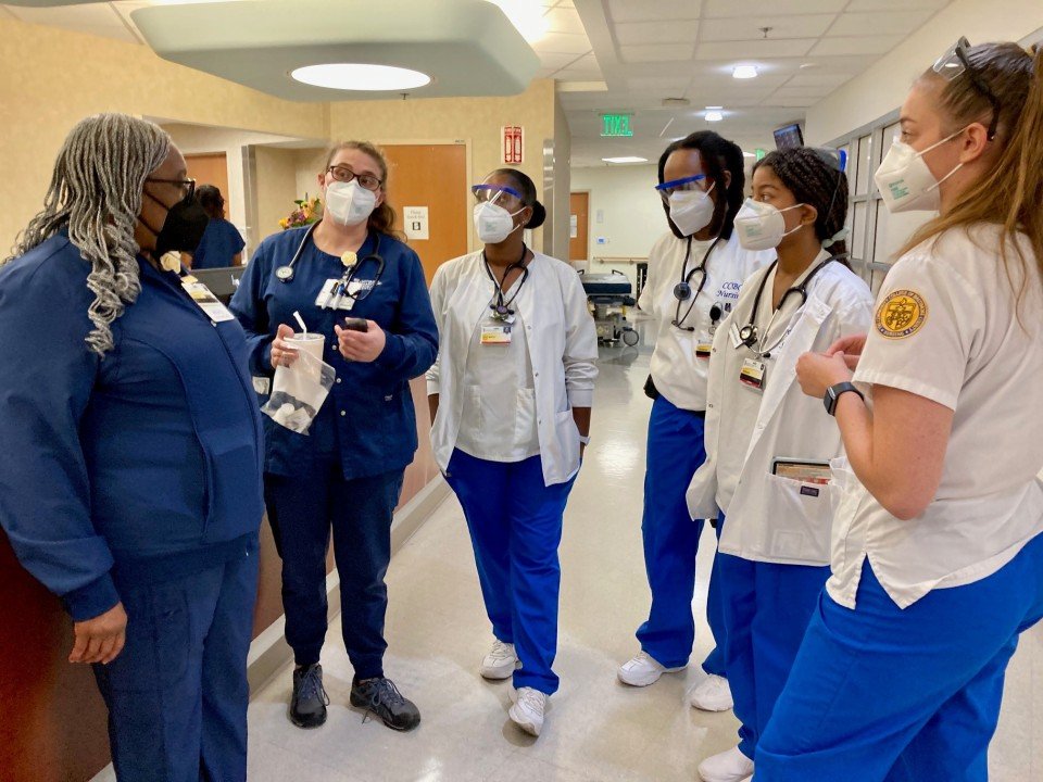 Two nurses reviewing a tablet together in a clinic hallway